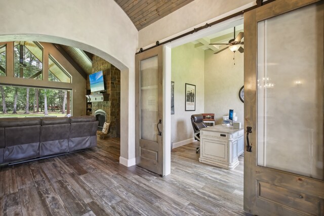 interior space featuring high vaulted ceiling, a stone fireplace, ceiling fan, wood-type flooring, and wood ceiling