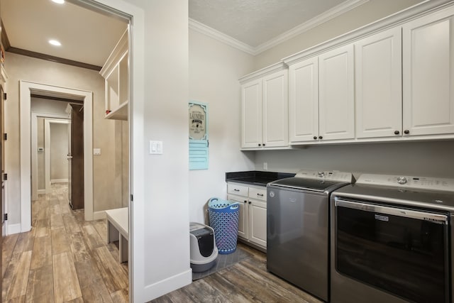 laundry room featuring separate washer and dryer, crown molding, dark hardwood / wood-style flooring, and cabinets