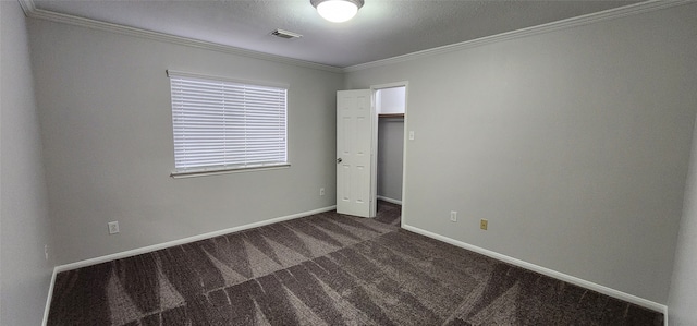 unfurnished bedroom featuring a closet, crown molding, and dark colored carpet