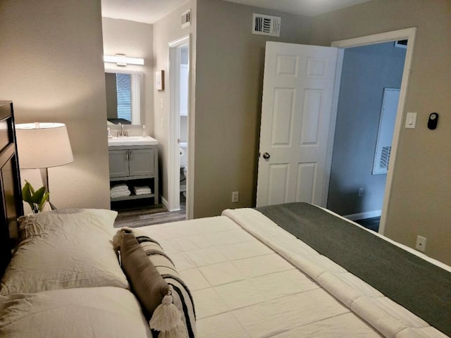 bedroom featuring hardwood / wood-style flooring, ensuite bath, and sink