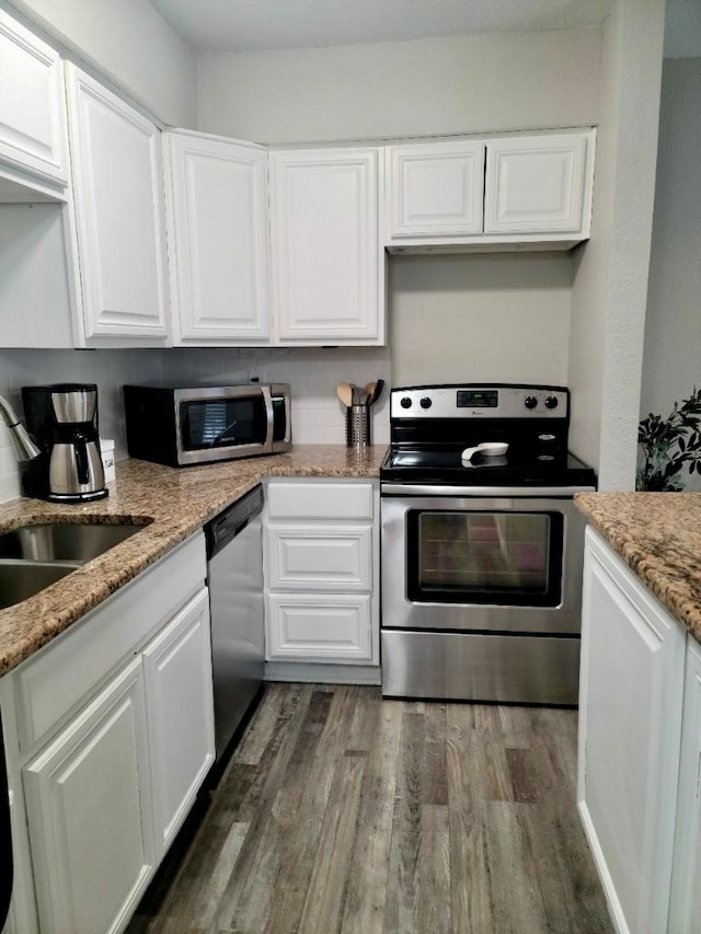 kitchen with stainless steel appliances, dark wood-type flooring, light stone counters, white cabinets, and sink