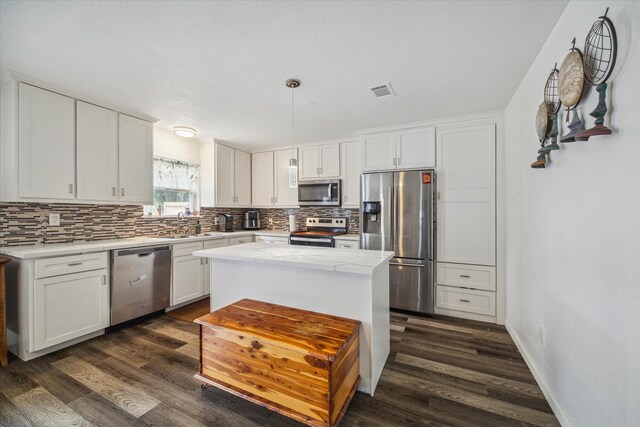 kitchen with white cabinetry, stainless steel appliances, dark wood-type flooring, and a kitchen island