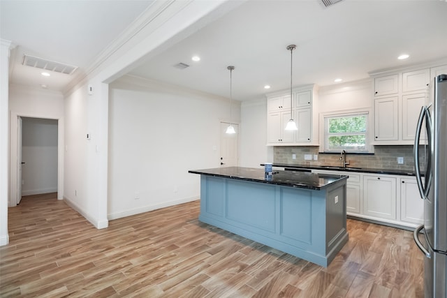 kitchen with light hardwood / wood-style flooring, a center island, pendant lighting, white cabinets, and stainless steel refrigerator