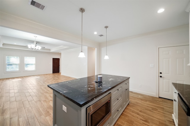 kitchen with appliances with stainless steel finishes, light hardwood / wood-style flooring, dark stone countertops, and a kitchen island