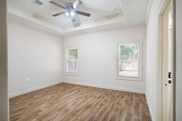 unfurnished room with crown molding, a raised ceiling, a wealth of natural light, and light wood-type flooring