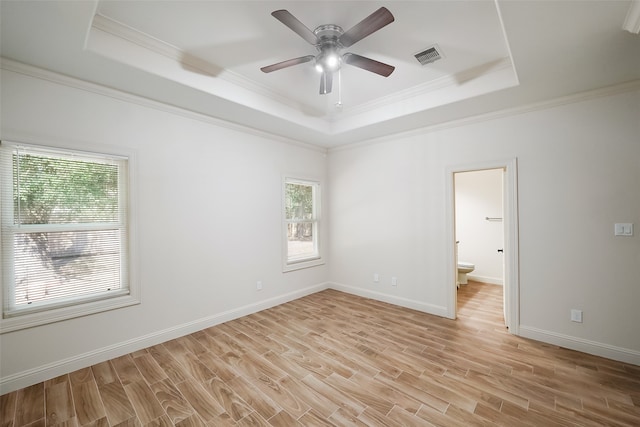 empty room with ceiling fan, a raised ceiling, ornamental molding, and light hardwood / wood-style flooring