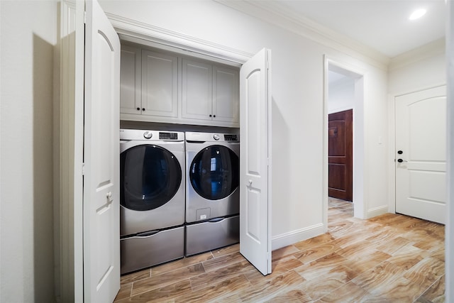 laundry room with cabinets, crown molding, washing machine and dryer, and light wood-type flooring