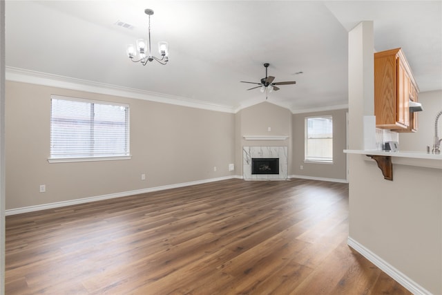 unfurnished living room with lofted ceiling, a premium fireplace, ornamental molding, ceiling fan with notable chandelier, and dark hardwood / wood-style flooring