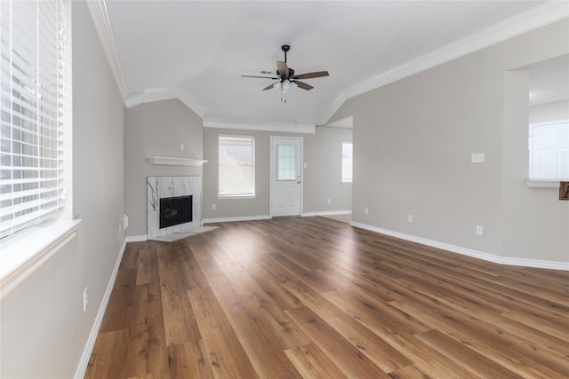 unfurnished living room with hardwood / wood-style floors, ceiling fan, vaulted ceiling, a fireplace, and crown molding