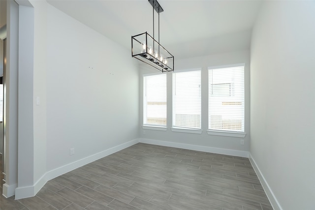 unfurnished dining area with a notable chandelier, a wealth of natural light, and light wood-type flooring