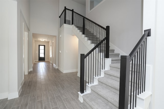 foyer entrance featuring a towering ceiling and wood-type flooring