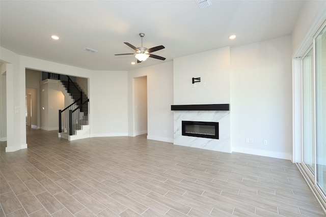 unfurnished living room featuring a fireplace, light hardwood / wood-style floors, and ceiling fan