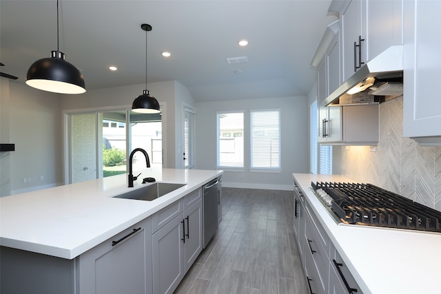 kitchen featuring extractor fan, an island with sink, hanging light fixtures, stainless steel appliances, and sink