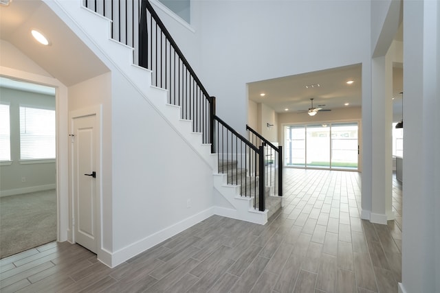 interior space featuring a towering ceiling, wood-type flooring, and ceiling fan