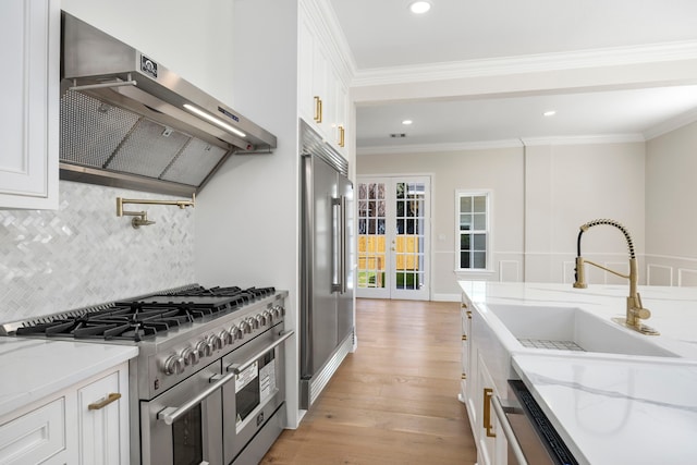 kitchen featuring high quality appliances, light stone countertops, and white cabinets