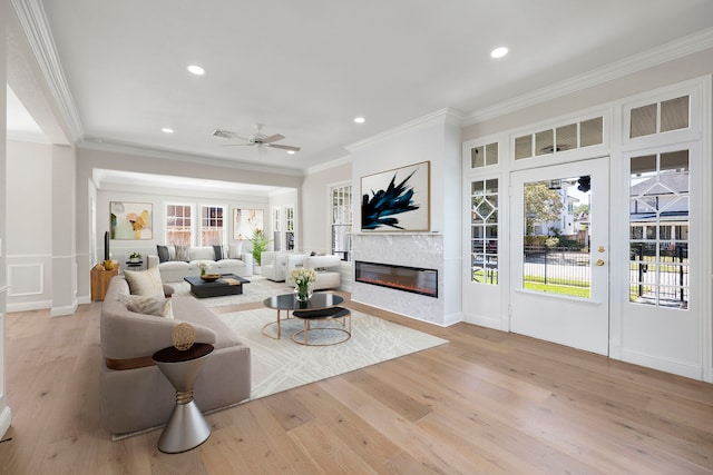 living room with ornamental molding, light hardwood / wood-style floors, and ceiling fan