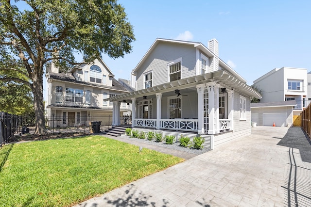 view of front of home featuring a porch, a front lawn, ceiling fan, an outbuilding, and a garage