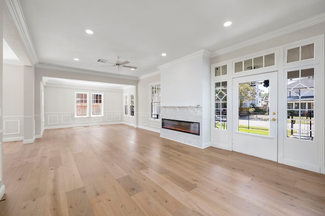 unfurnished living room with crown molding, light wood-type flooring, and ceiling fan