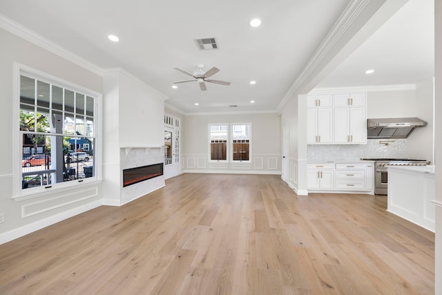 unfurnished living room with ornamental molding, light wood-type flooring, and ceiling fan