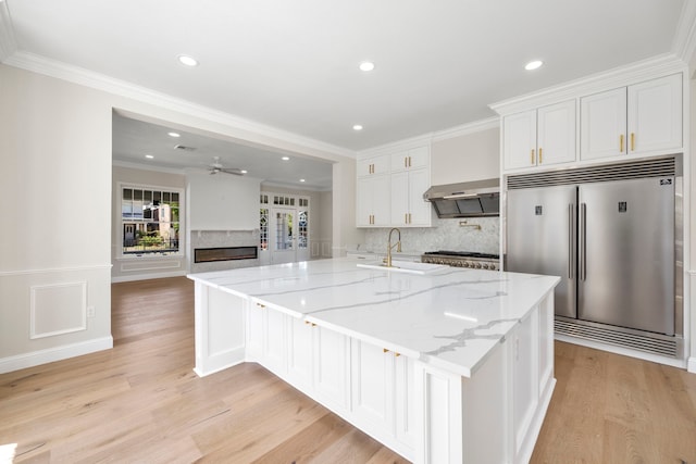 kitchen featuring light hardwood / wood-style flooring, white cabinets, light stone counters, and stainless steel appliances