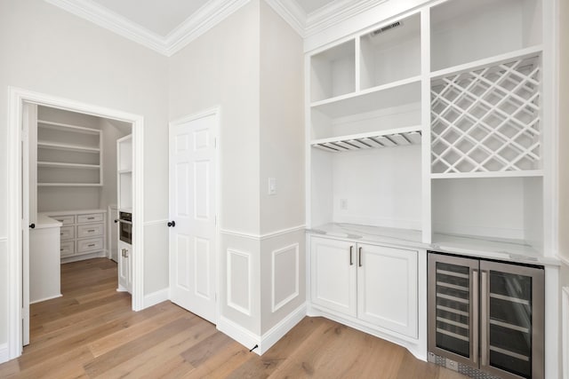 hall with light hardwood / wood-style floors, crown molding, and beverage cooler