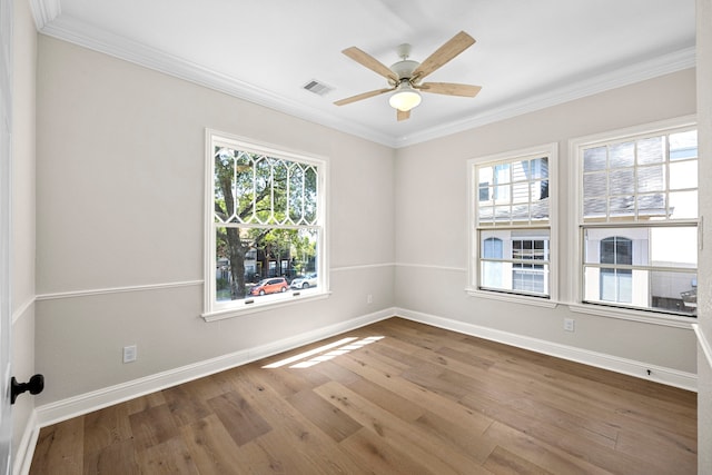 spare room with ornamental molding, a healthy amount of sunlight, and hardwood / wood-style flooring