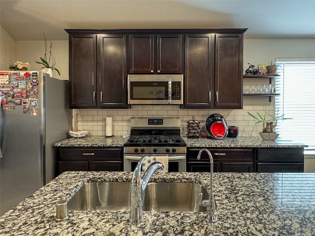 kitchen featuring light stone counters, dark brown cabinetry, stainless steel appliances, and backsplash