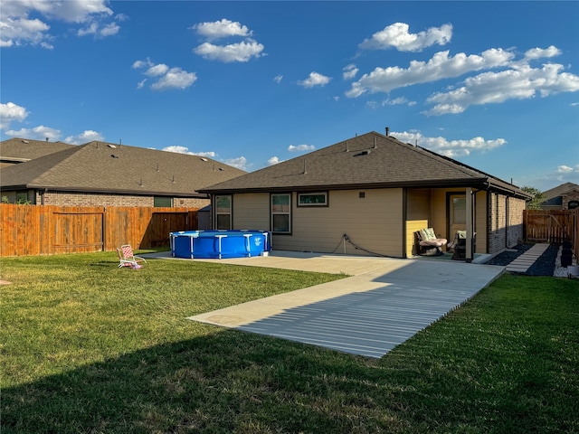 back of property with a yard, a patio, and a fenced in pool