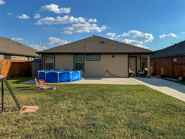 back of house featuring a yard, a patio, and a fenced in pool