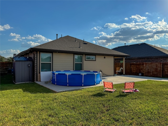 rear view of house with a patio, a fenced in pool, and a lawn