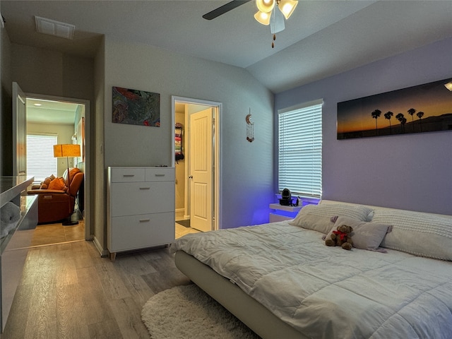 bedroom with lofted ceiling, ceiling fan, multiple windows, and hardwood / wood-style flooring