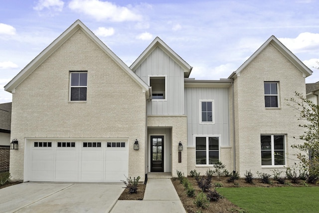 view of front of house with an attached garage, board and batten siding, driveway, a front lawn, and brick siding