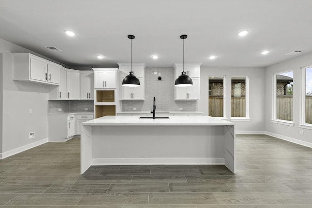kitchen featuring visible vents, tasteful backsplash, a spacious island, and a sink