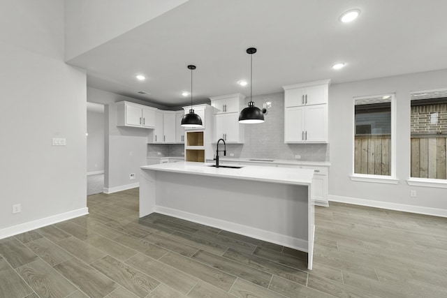 kitchen featuring light wood-type flooring, white cabinets, a sink, and decorative backsplash