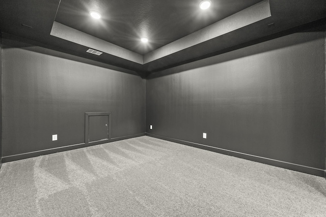 carpeted empty room with a tray ceiling, baseboards, visible vents, and recessed lighting