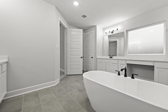 bathroom featuring visible vents, a soaking tub, baseboards, tile patterned floors, and vanity