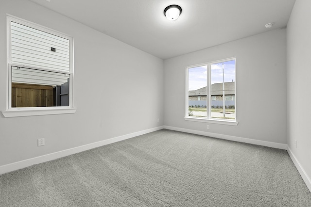 carpeted empty room featuring baseboards