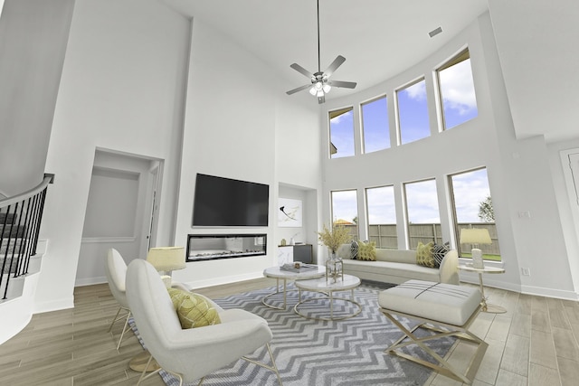 living area featuring a ceiling fan, visible vents, stairway, and wood finished floors