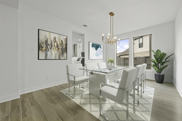 dining area with wood tiled floor, visible vents, baseboards, and an inviting chandelier