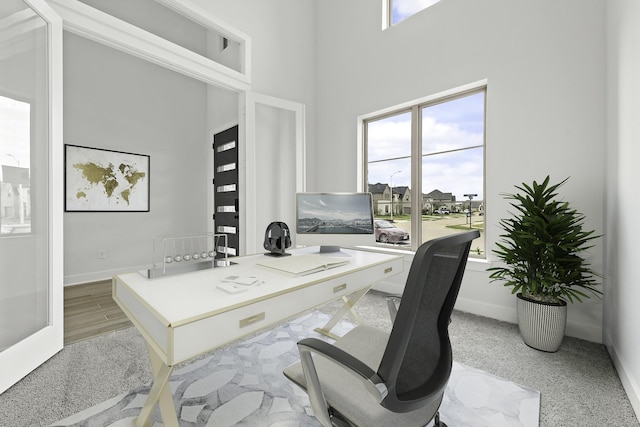 office space with baseboards and a towering ceiling