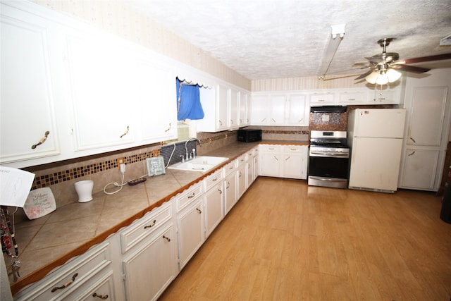 kitchen with sink, white cabinets, white fridge, tile counters, and stainless steel range