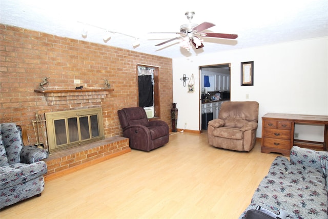 living room with hardwood / wood-style flooring, ceiling fan, and a fireplace