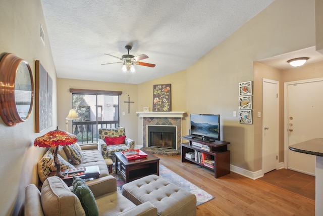 living room featuring a fireplace, a textured ceiling, ceiling fan, lofted ceiling, and hardwood / wood-style flooring