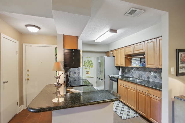 kitchen featuring sink, kitchen peninsula, stainless steel appliances, and backsplash