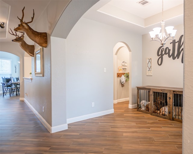 hall with hardwood / wood-style floors and an inviting chandelier