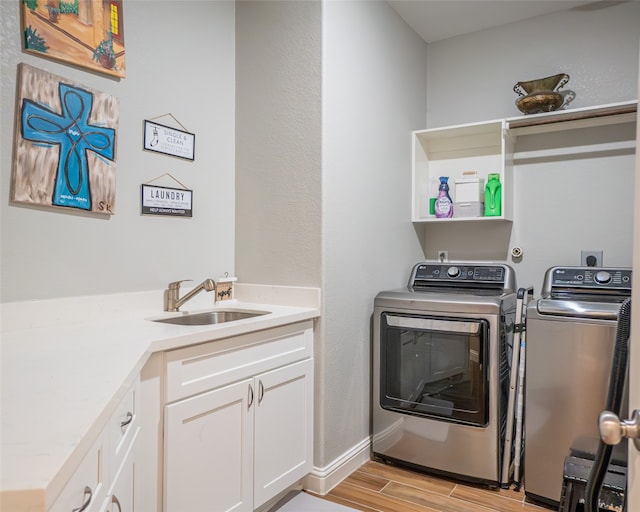 laundry area with light wood-type flooring, separate washer and dryer, and sink