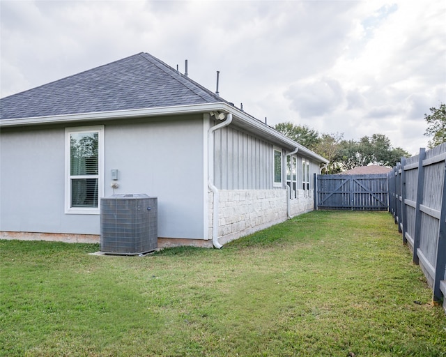 view of side of property featuring a lawn and central AC