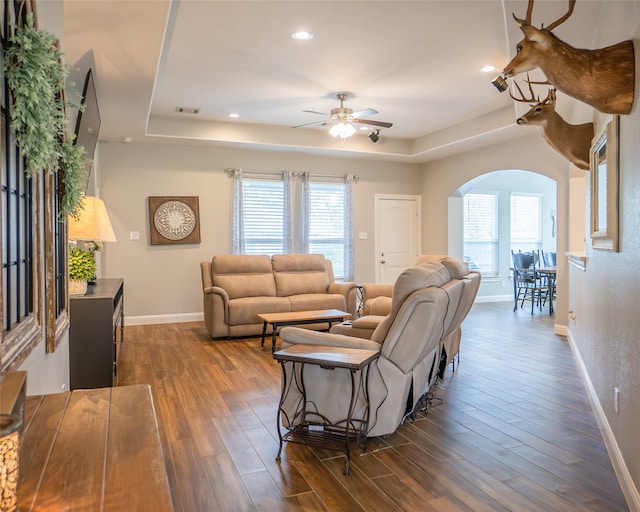 living room with ceiling fan, dark hardwood / wood-style floors, plenty of natural light, and a tray ceiling