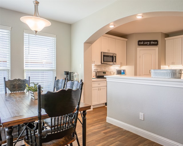 kitchen with white cabinets, dark hardwood / wood-style floors, hanging light fixtures, and tasteful backsplash