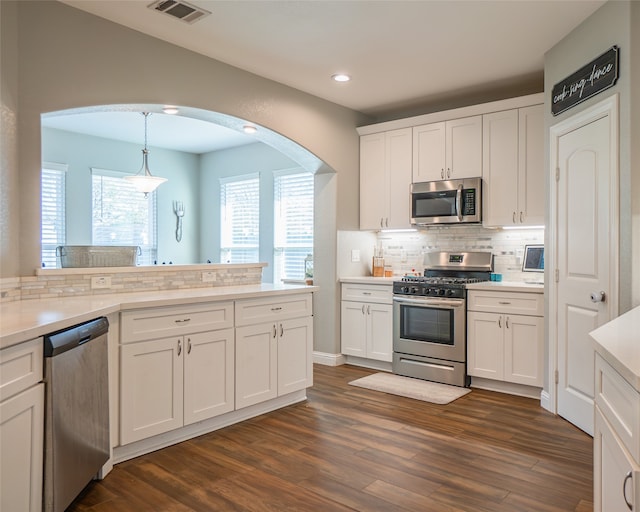 kitchen with stainless steel appliances, dark hardwood / wood-style floors, white cabinetry, and decorative light fixtures